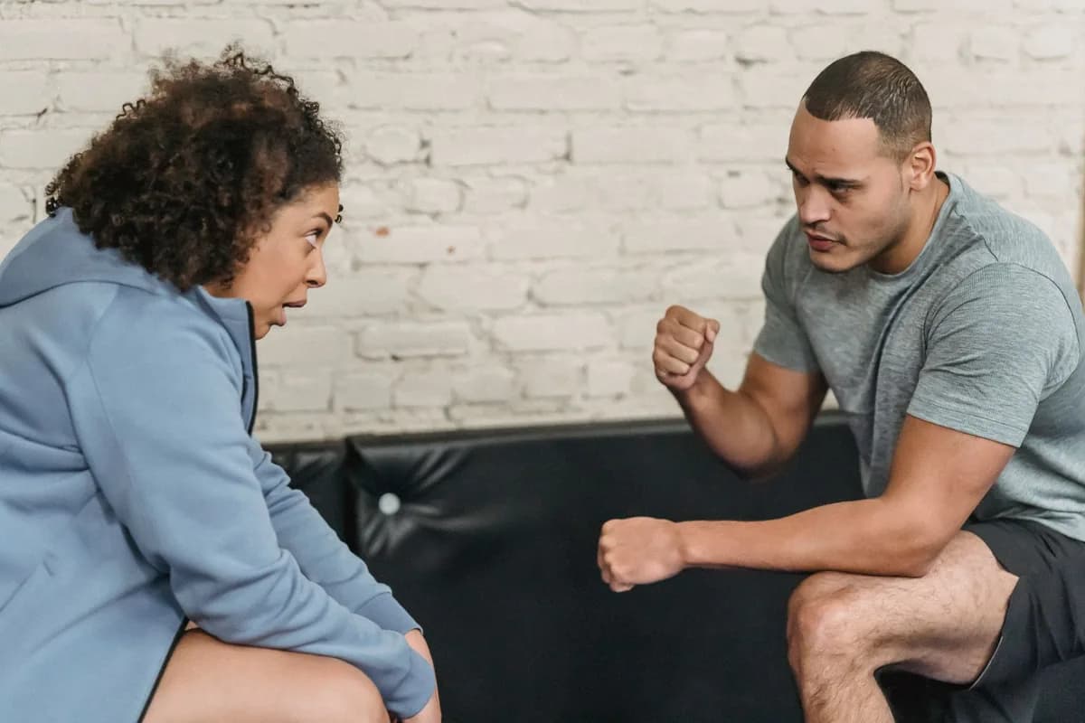 Personal trainer e aluna sentados frente a frente, conversando durante o atendimento no estúdio