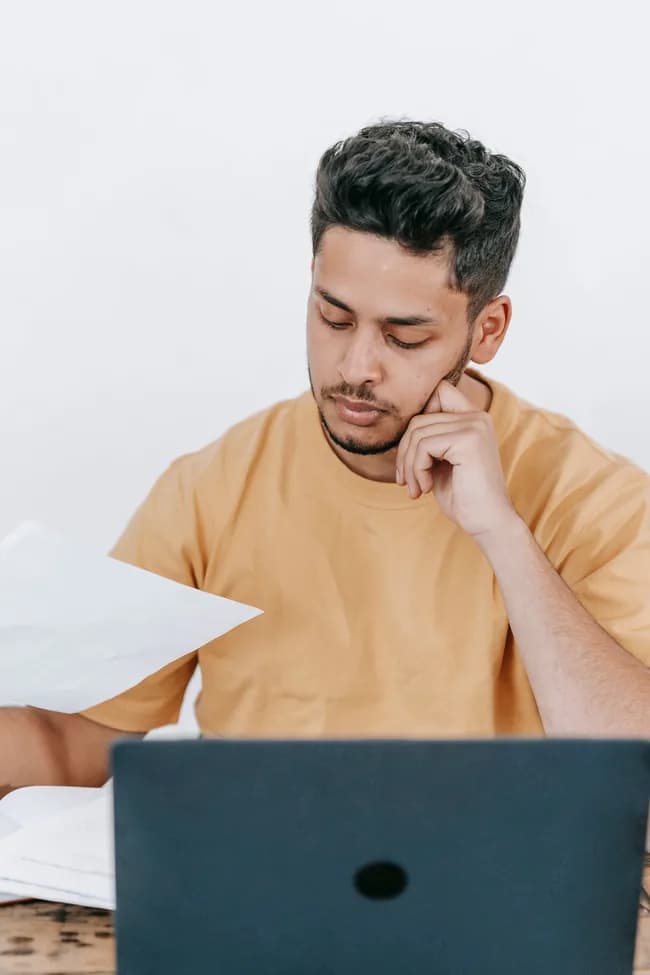 Prestador de serviço lendo um documento com o notebook aberto à frente