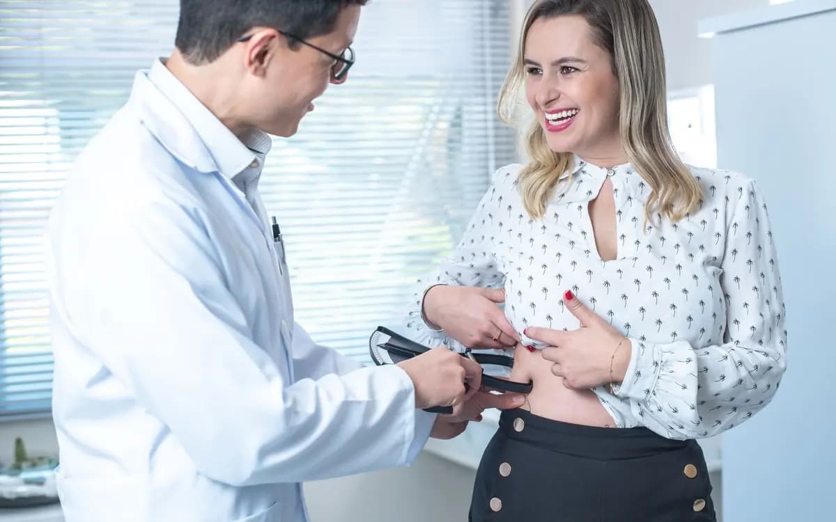 Nutricionista fazendo avaliação corporal com adipômetro em uma paciente sorridente no consultório