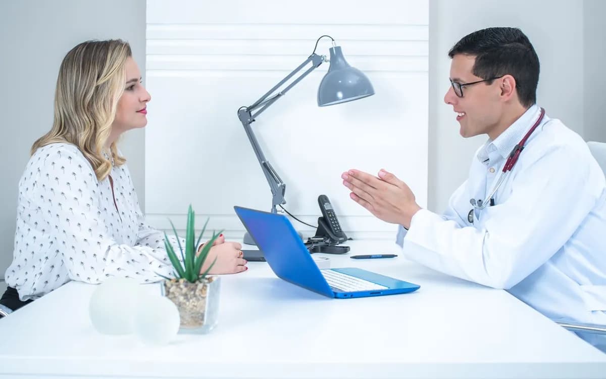 Nutricionista conversando com uma paciente à mesa do consultório durante a consulta