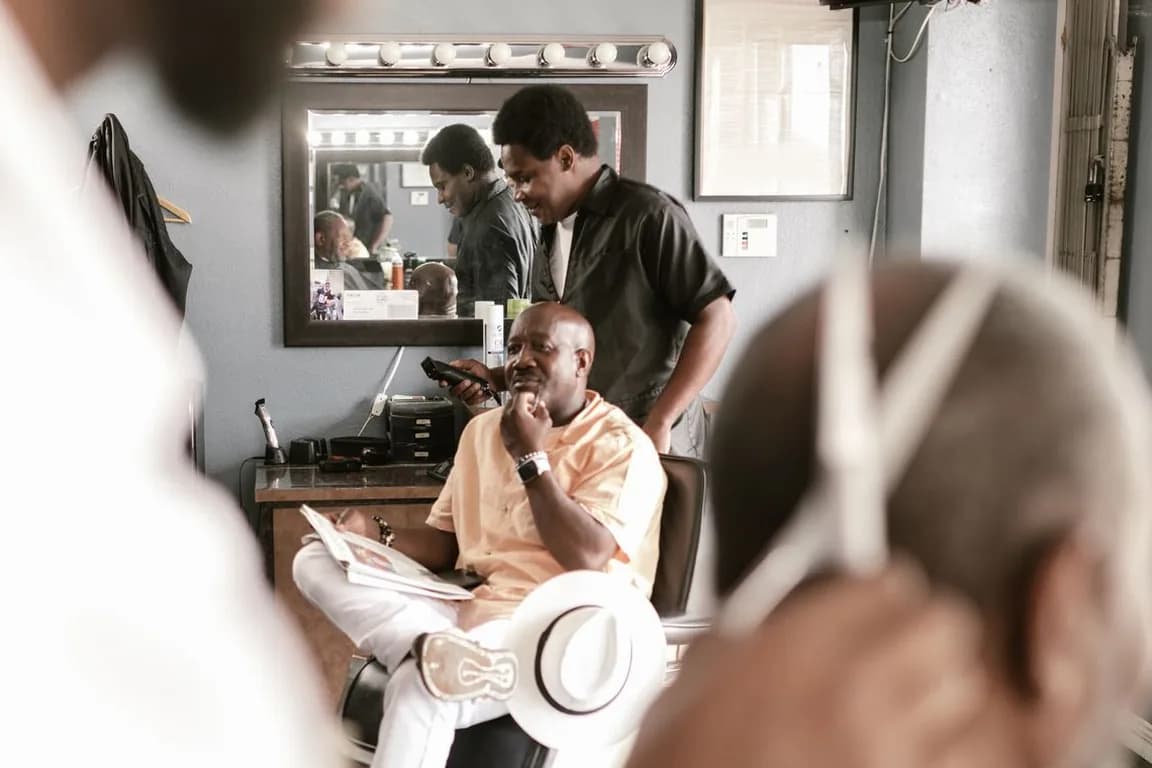Barbearia com dois barbeiros atendendo ao mesmo tempo, estação de trabalho e espelho de camarim