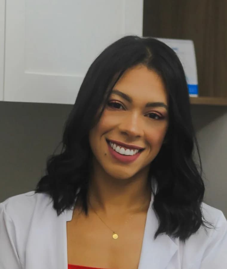 Nutricionista de jaleco sorrindo no consultório